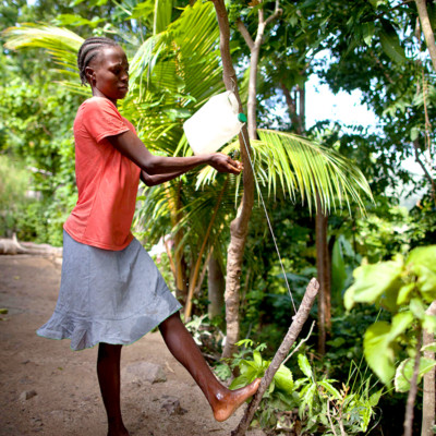 Miscaden Ronel, washes her hands at a simple hand washing station set up at her home.