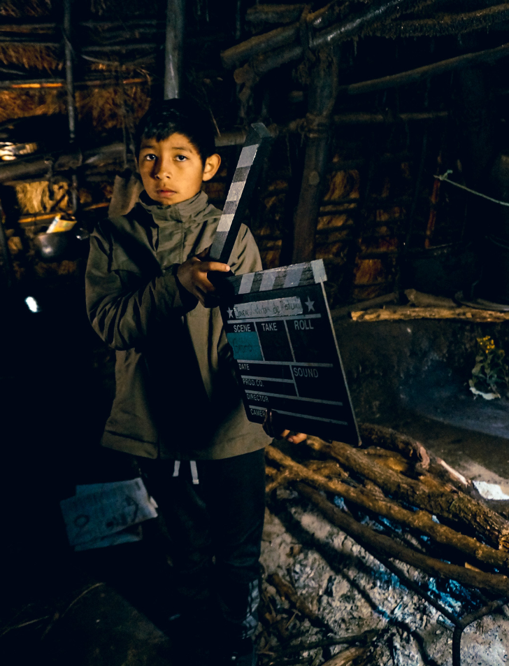 An Indigenous youth holds a film clapper board