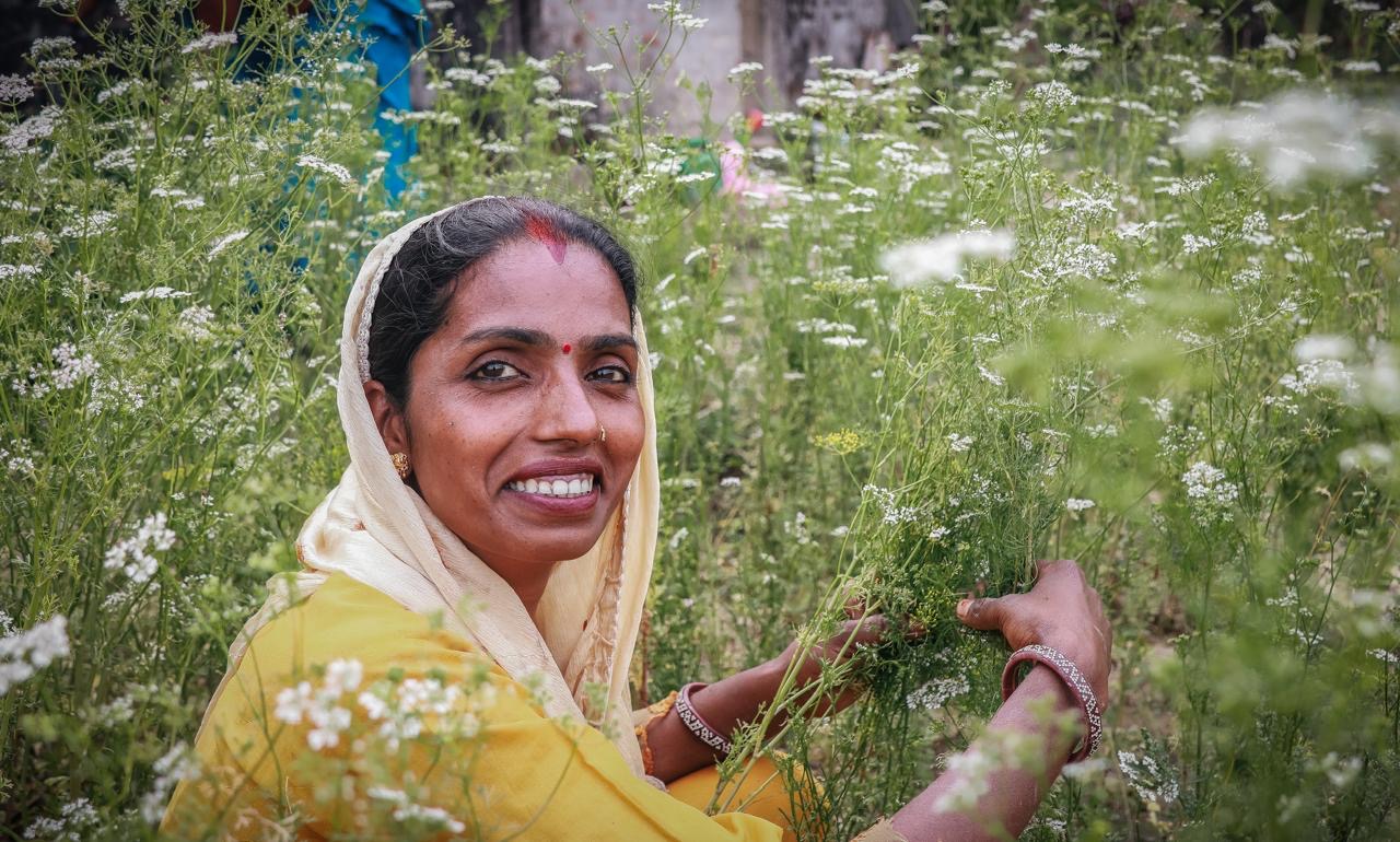 A woman farmer in Nepal wearing traditional clothing sitting in a field